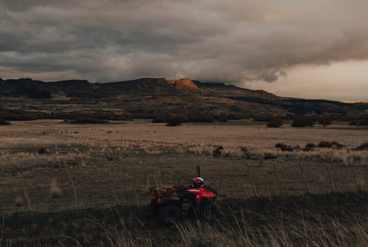 ATV in a field with high ground behind. Photo by Gaspar Zaldo: https://www.pexels.com/photo/red-and-black-atv-on-brown-grass-field-near-mountain-8798122/