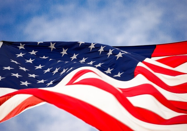 U.S. flag waving in the wind with a bright blue cloudy sky in the background. Stroud National Agency, Inc. celebrates Memorial Day 2023