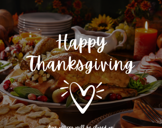 A photo of a Thanksgiving meal on a table with the following centered in front of it in white font: "Happy Thanksgiving", a white outlined heart, and"Our offices will be closed on Thursday, November 23rd & Friday, November 24th."