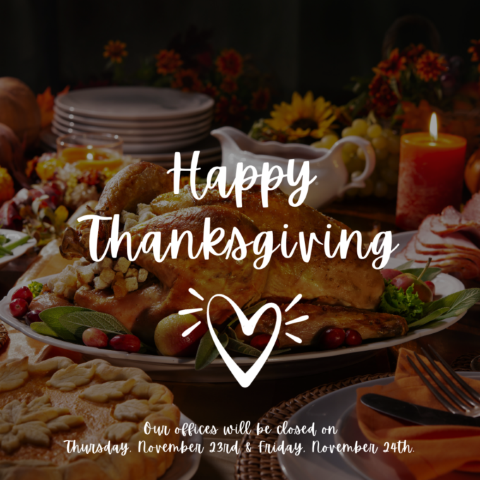 A photo of a Thanksgiving meal on a table with the following centered in front of it in white font: "Happy Thanksgiving", a white outlined heart, and"Our offices will be closed on Thursday, November 23rd & Friday, November 24th."